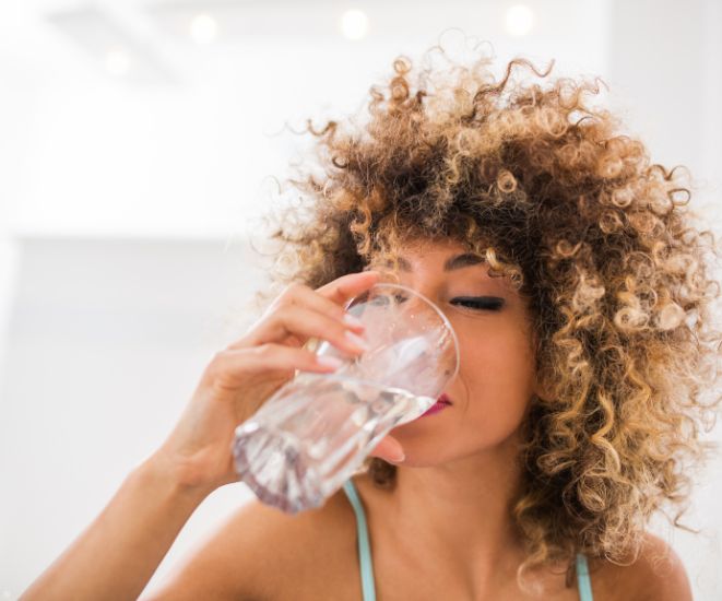 A woman drinking a glass of water.
